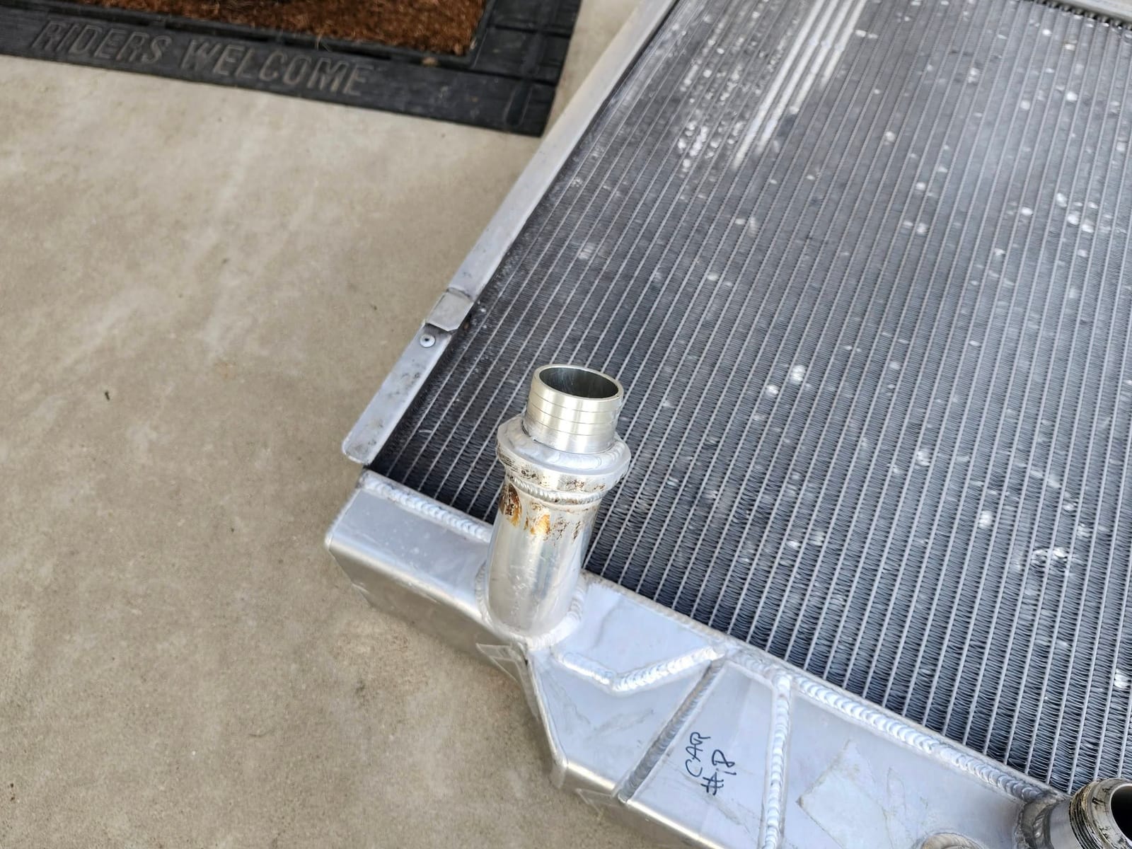 A new hose neck TIG welded onto an aluminum radiator end tank, with the fresh bead still bare