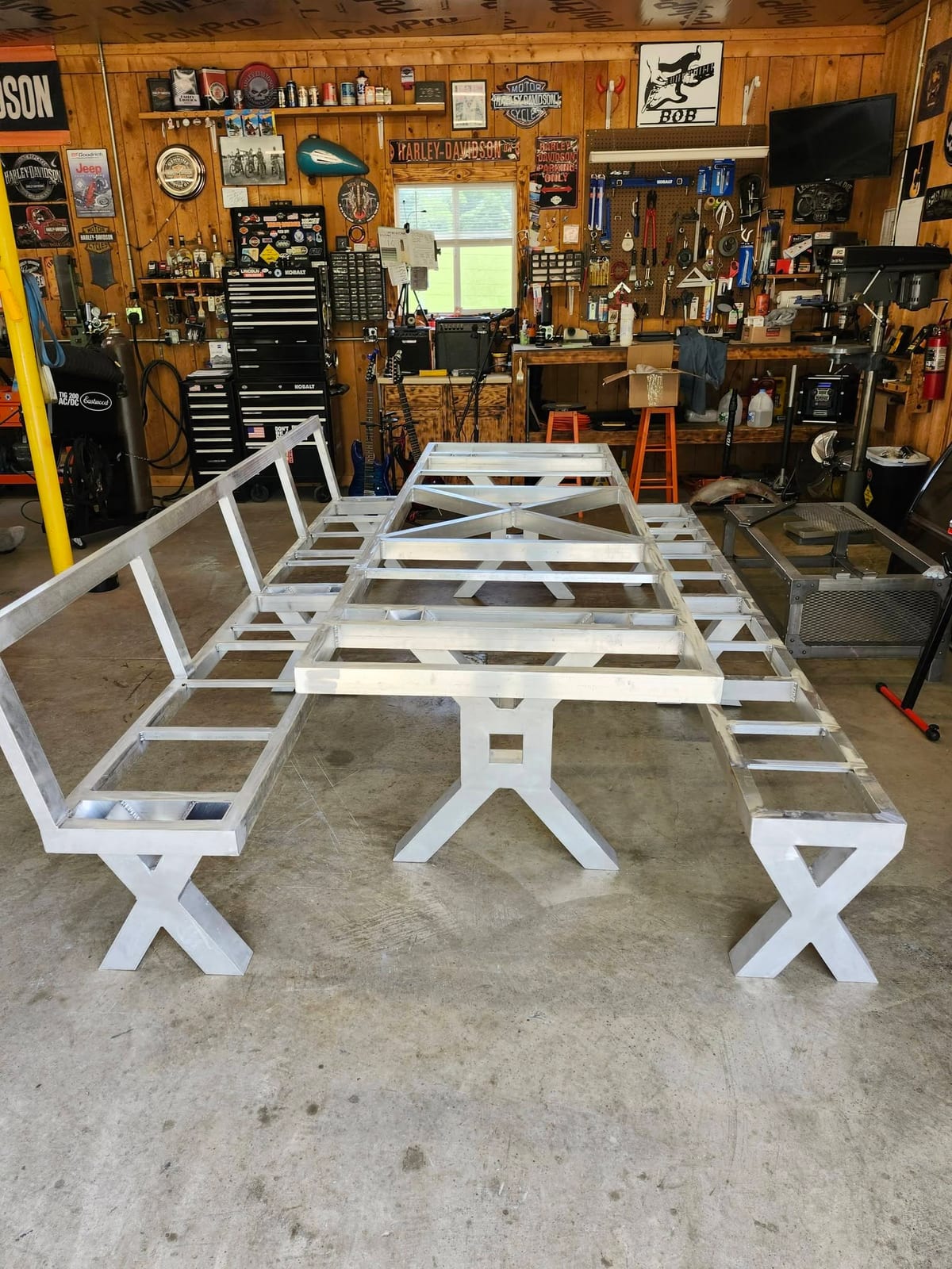 A full aluminum picnic table and bench set framed up in bare metal on the floor of the shop