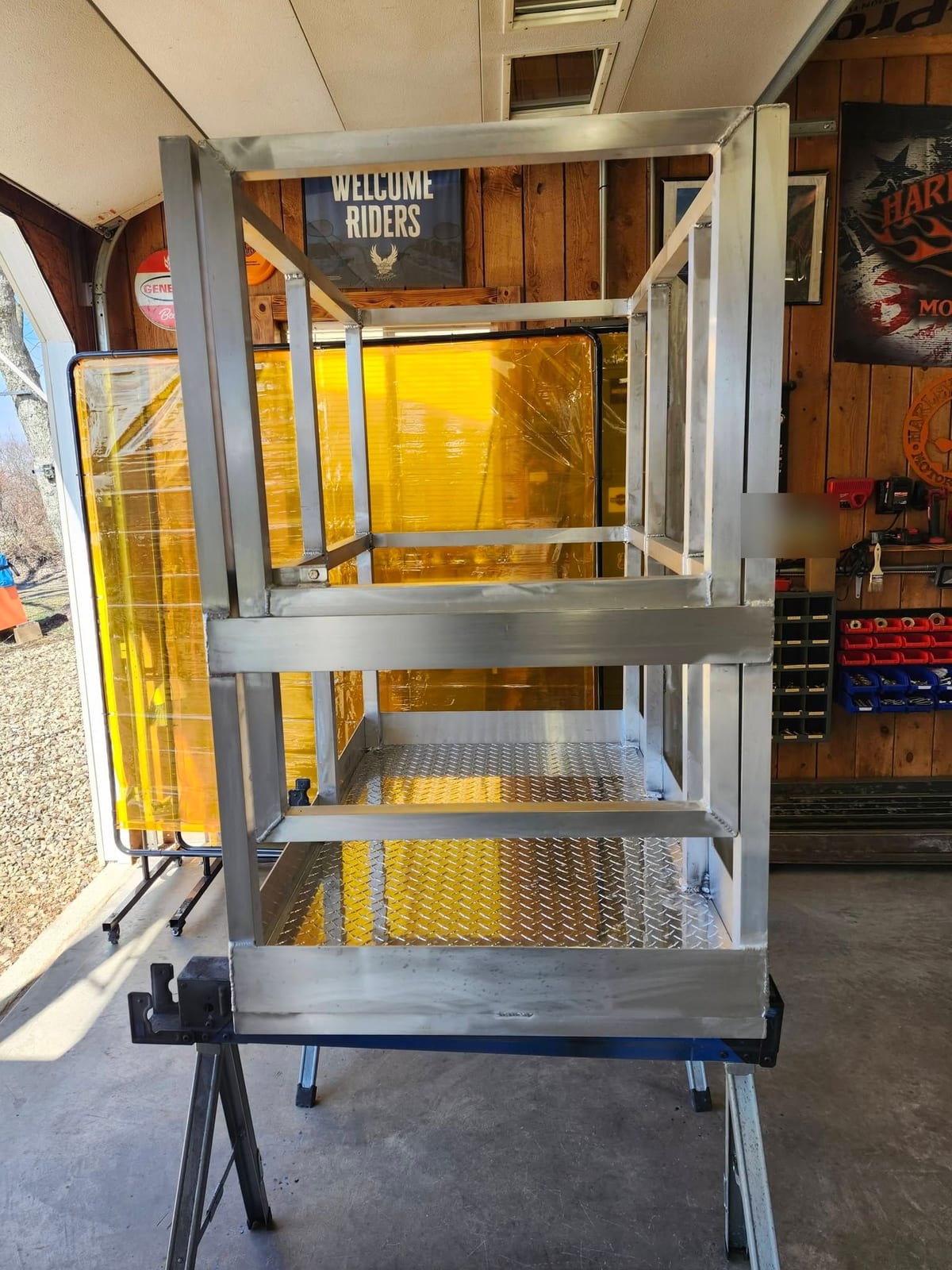 An aluminum man basket with the safety gate closed, standing in the doorway of the shop