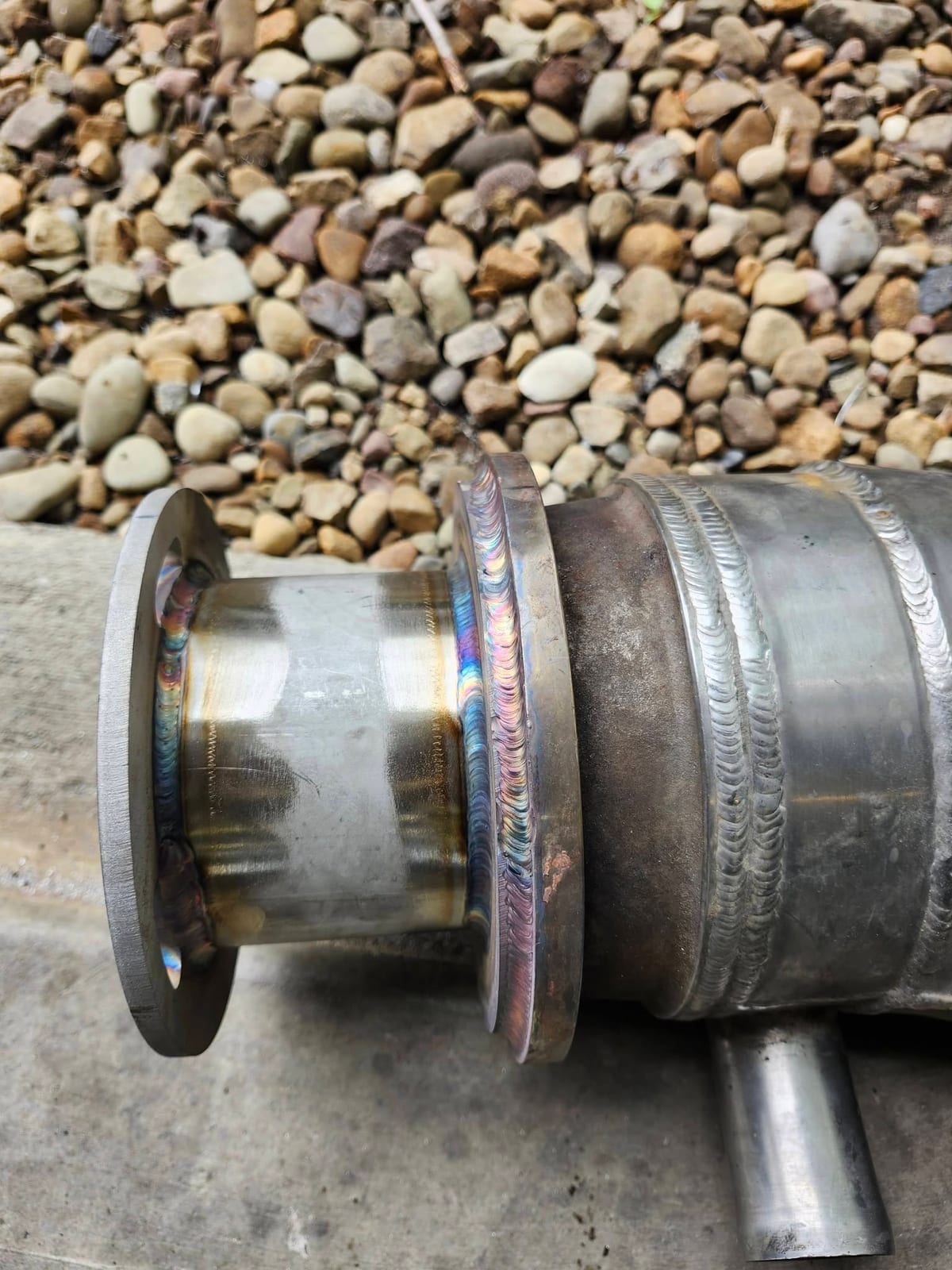 A TIG welded stainless steel pipe flange showing rainbow heat tint around the bead