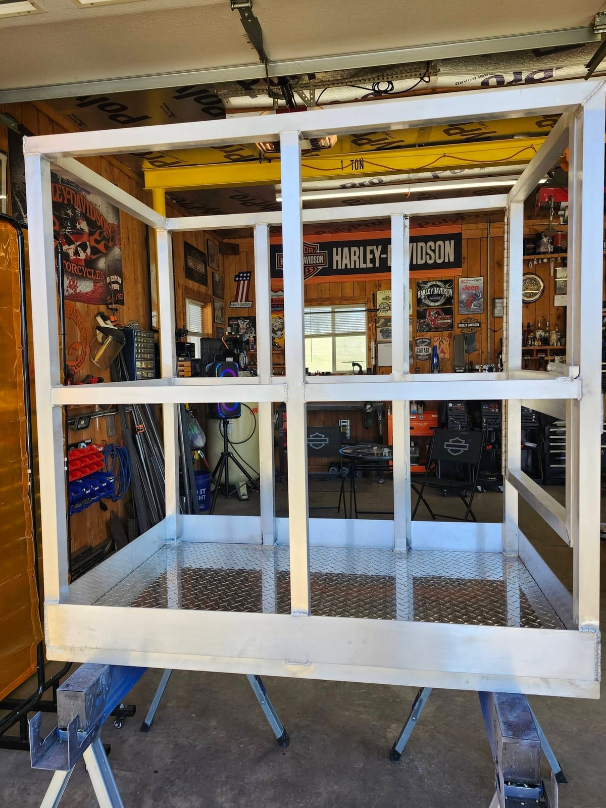 A large welded aluminum man basket with a diamond plate floor standing in the doorway of the Robinson Welding shop