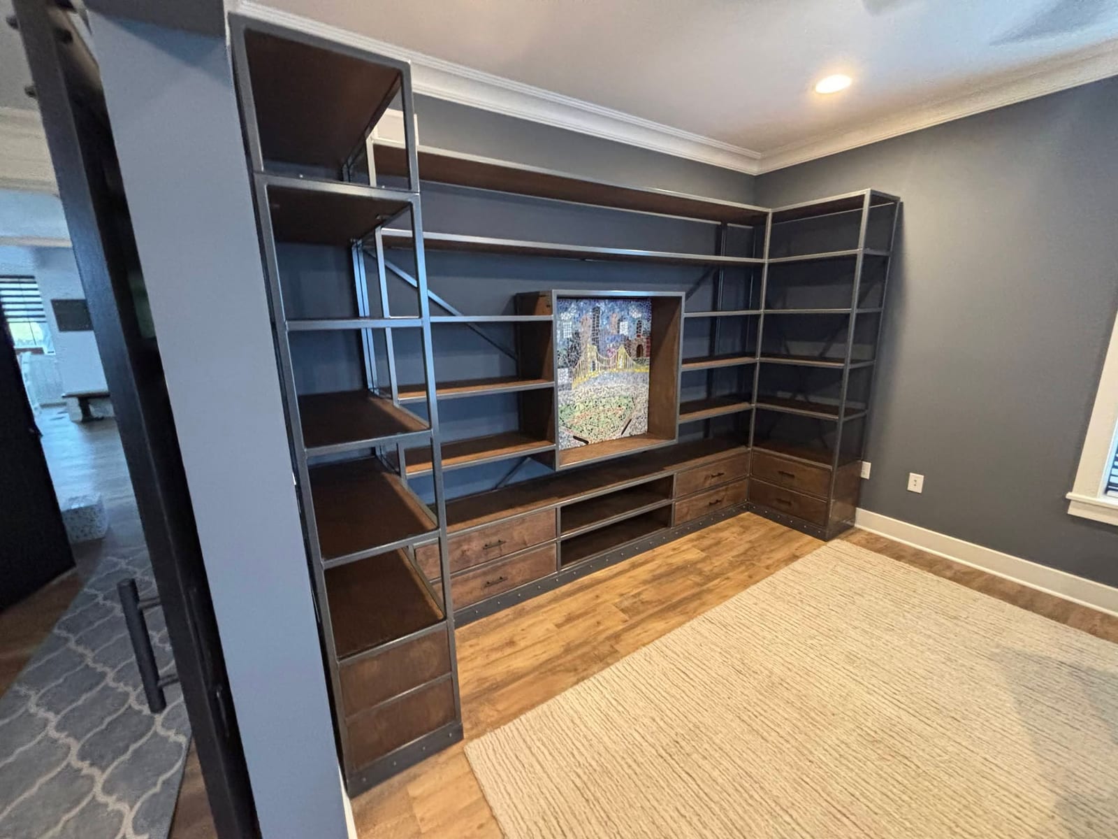 A custom steel frame and wood built-in shelving wall unit installed in a client's living room