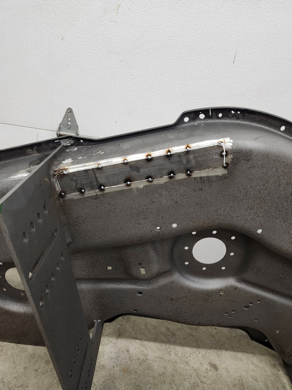A replacement patch plate clamped into a cut-out in a steel body panel with the first stitch weld running along the seam