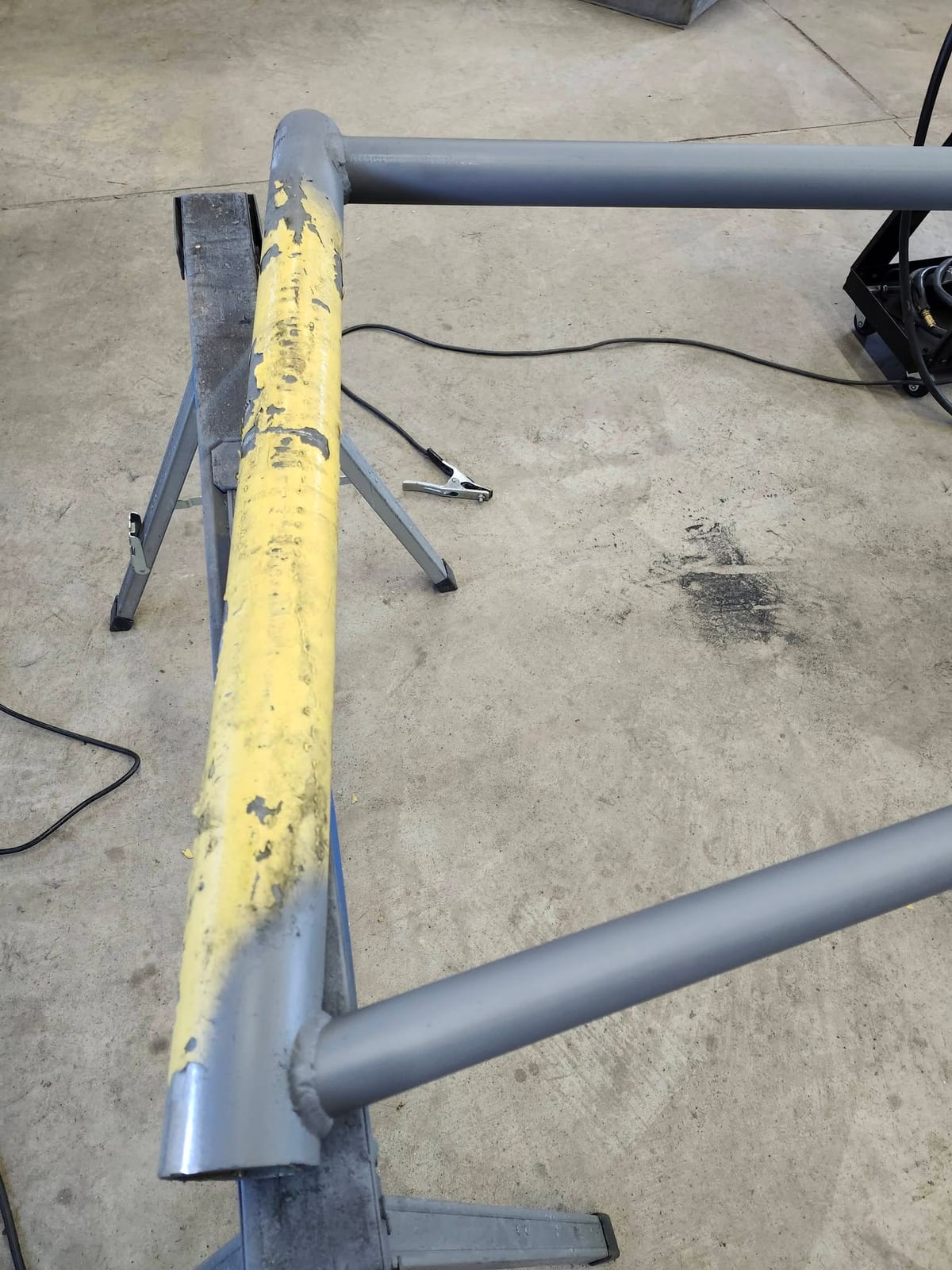 A new section of tube welded into an old yellow painted handrail on sawhorses in the shop