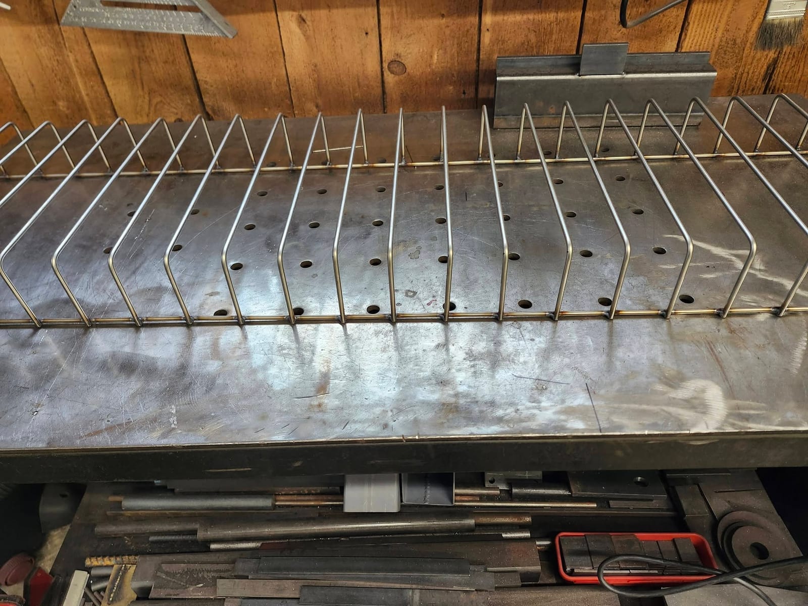 A stainless steel rib rack with evenly spaced welded rod dividers on the shop welding table